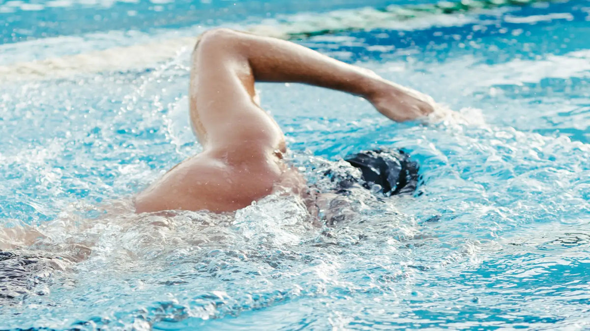 Close-up of a swimmer doing freestyle laps in a bright blue pool