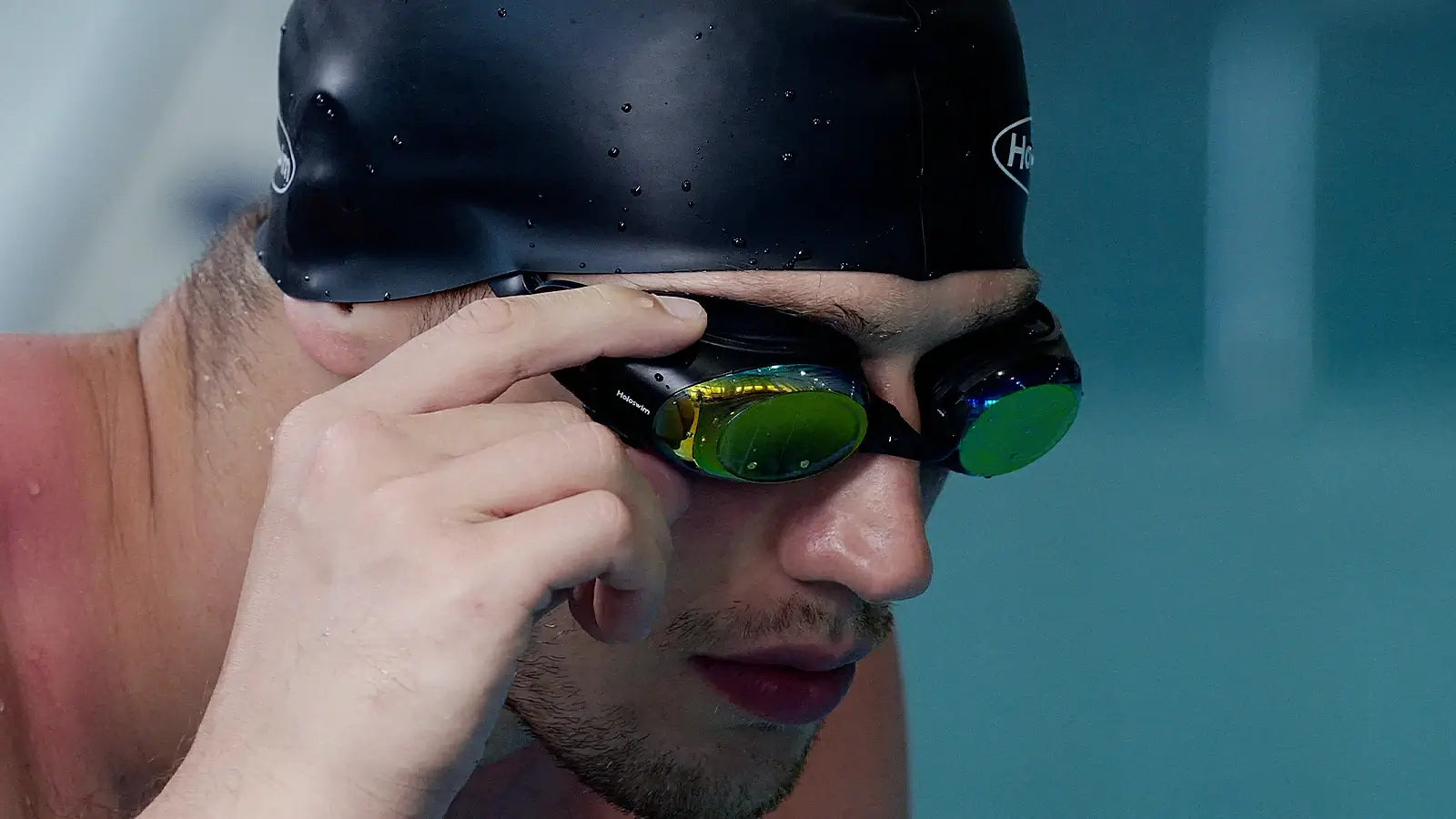 Close-up of male swimmer adjusting HoloSwim 3 Pro smart swim goggles before training