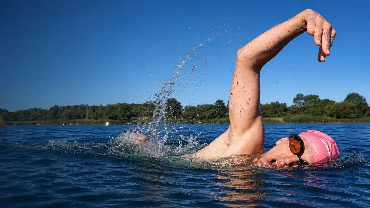 Open-water swimmer wearing goggles during freestyle beside a course buoy