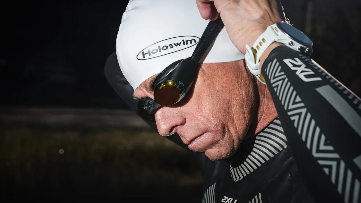 Open-water swimmer adjusting mirrored HoloSwim goggles before a swim